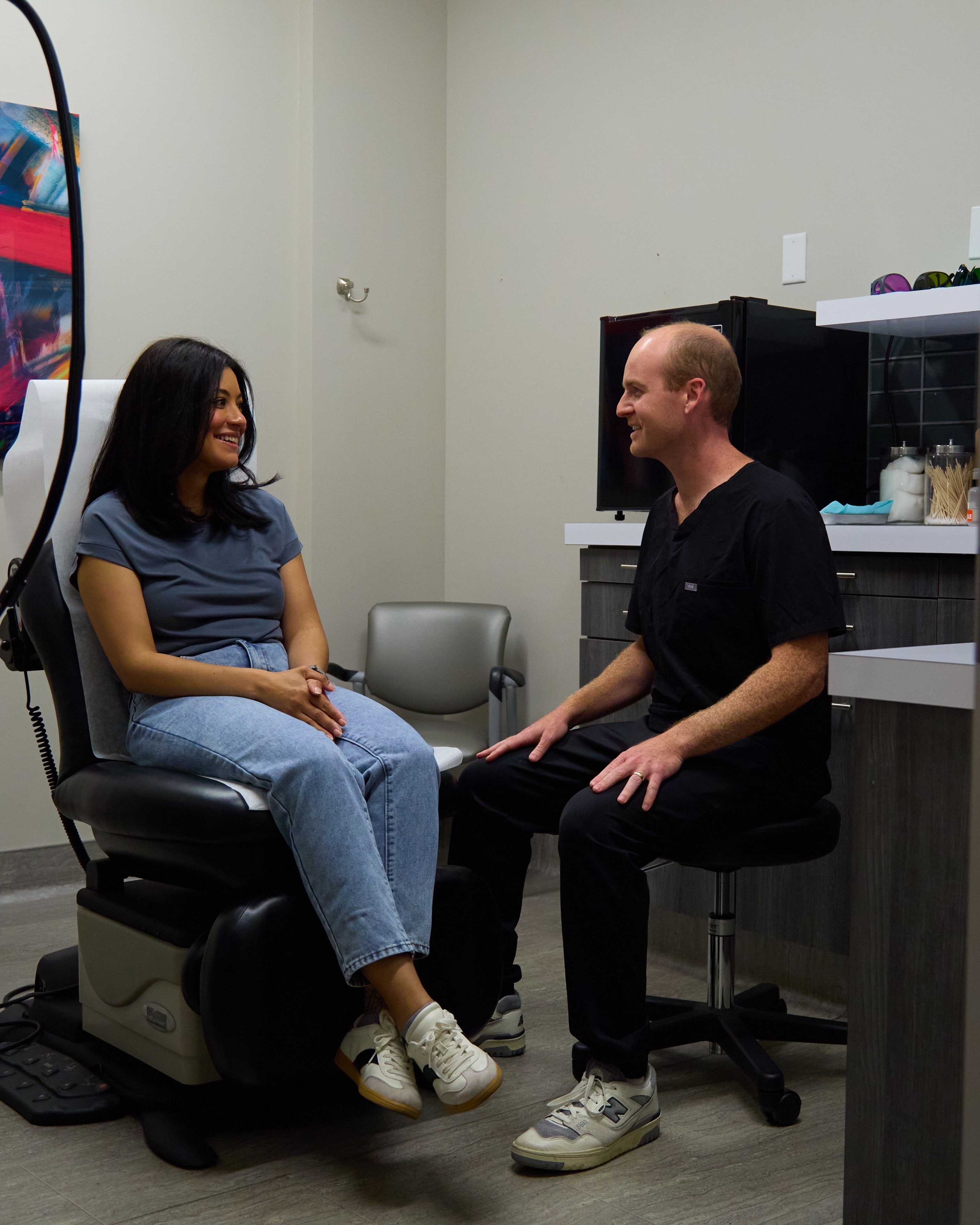 A Macias Dermatology clinician in unhurried conversation with a patient in the exam room