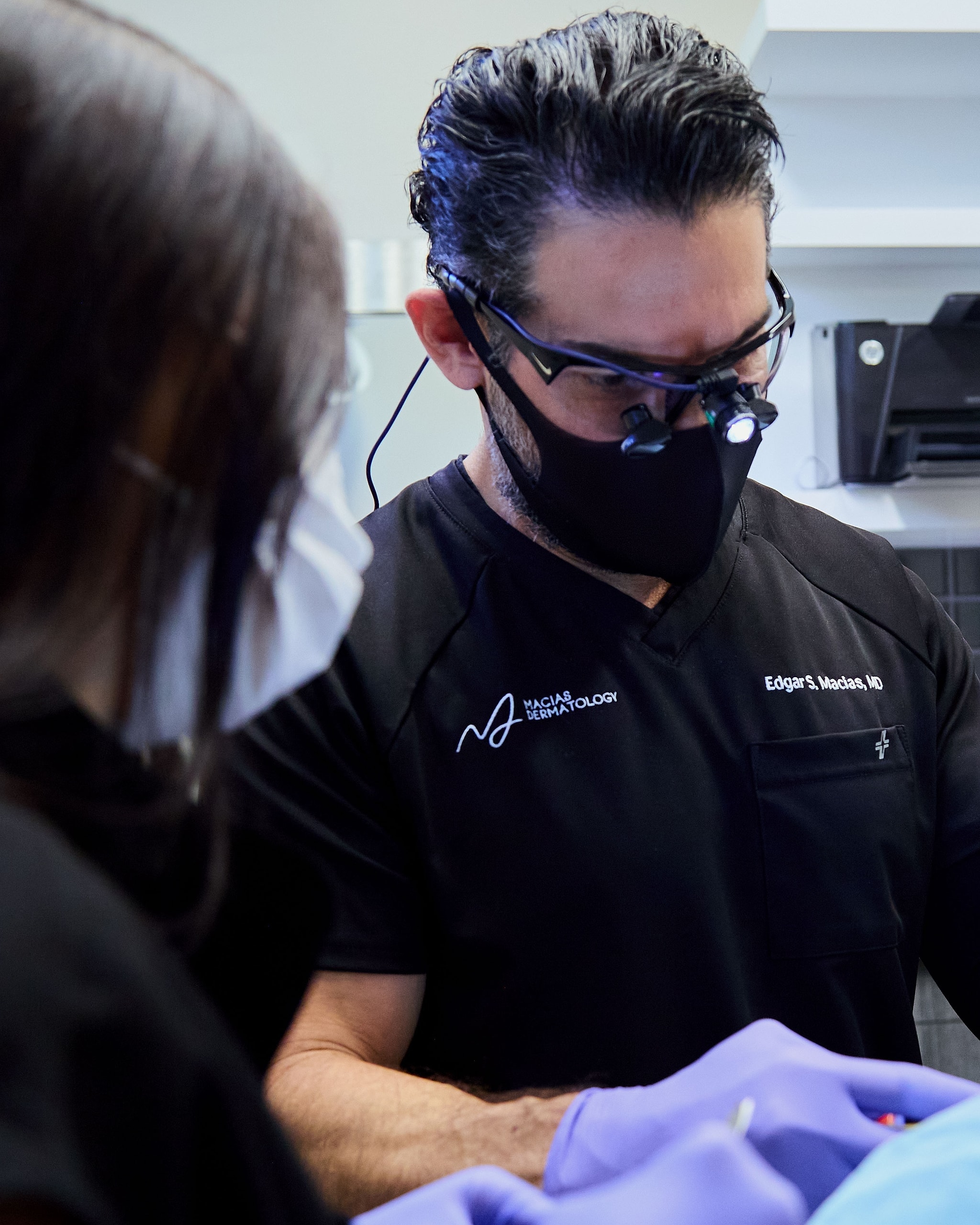 Dr. Edgar Macias in surgical loupes performing a procedure in the treatment room
